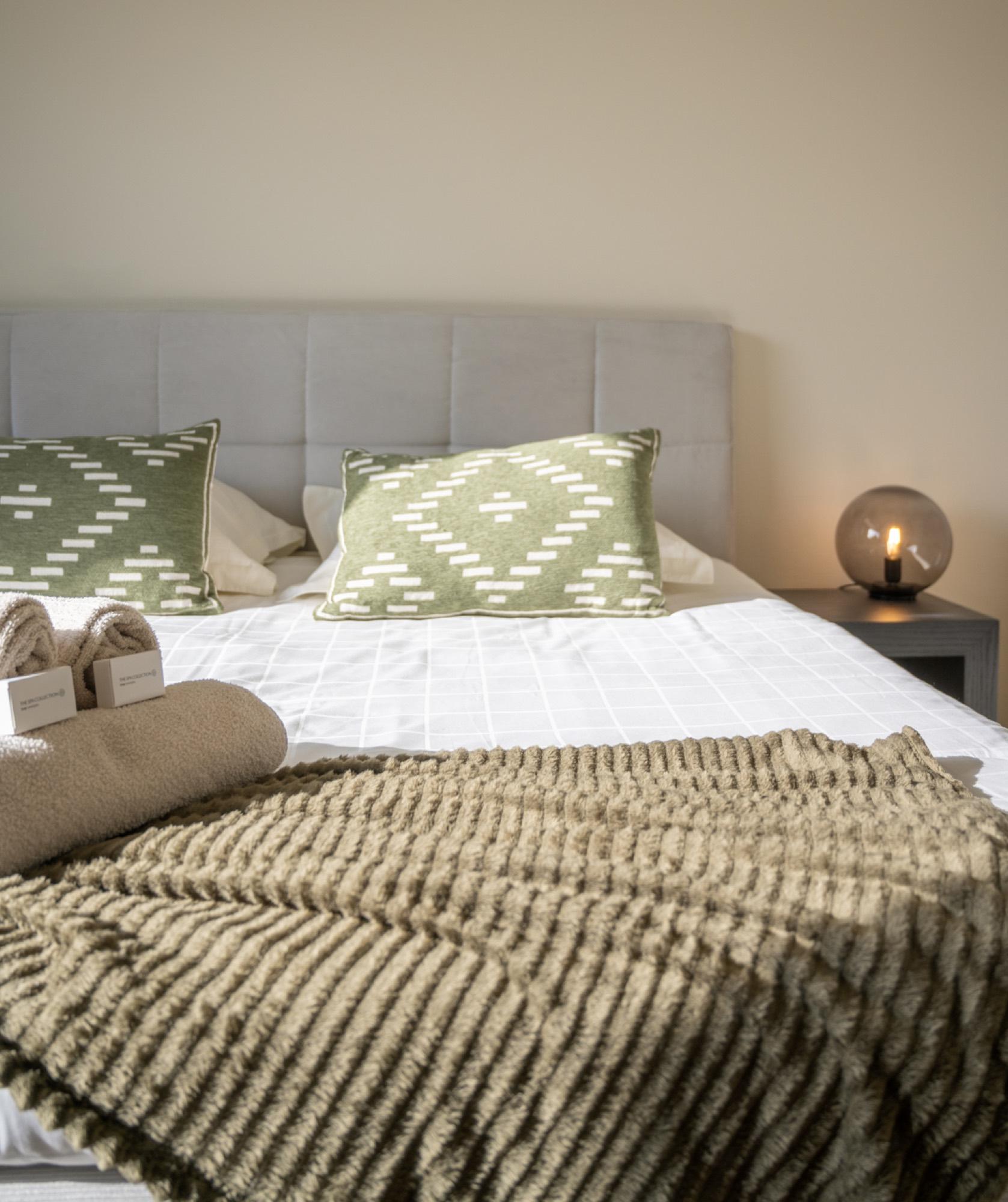 Bed met groene kussens en plaid